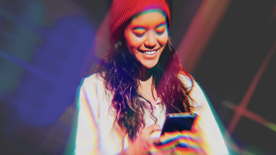 A smiling woman wearing a red hat and a white top against a dark background